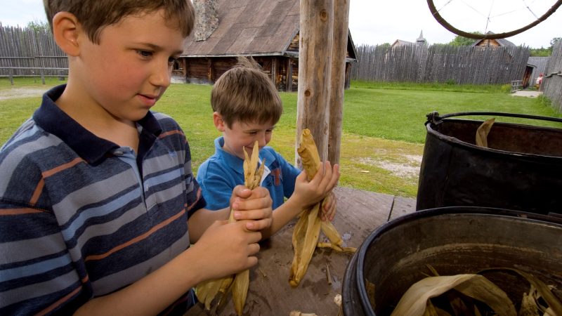 Deux jeunes visiteurs à créer des poupées d'épluche de maïs à Sainte-Marie