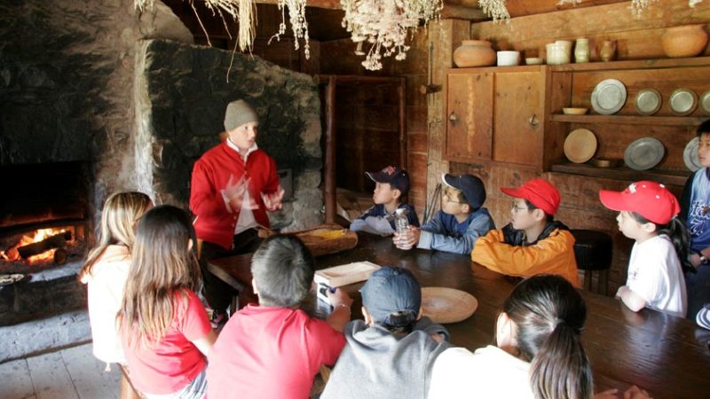 A historical interpreter talking to a group of young visitors in the cookhouse at Sainte-Marie among the Hurons
