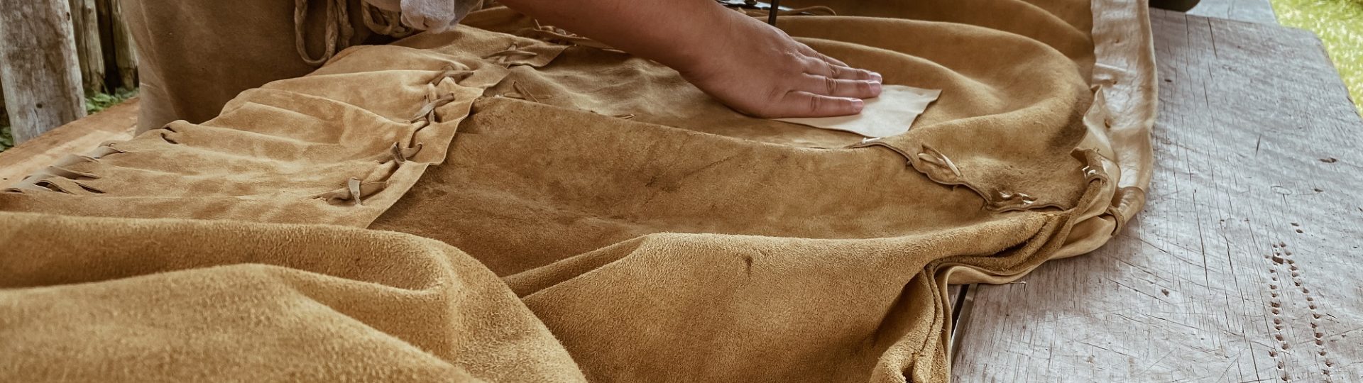 Une interprète historique autochtone à travailler sur un morceau de cuir - le début d'une paire de moccasins