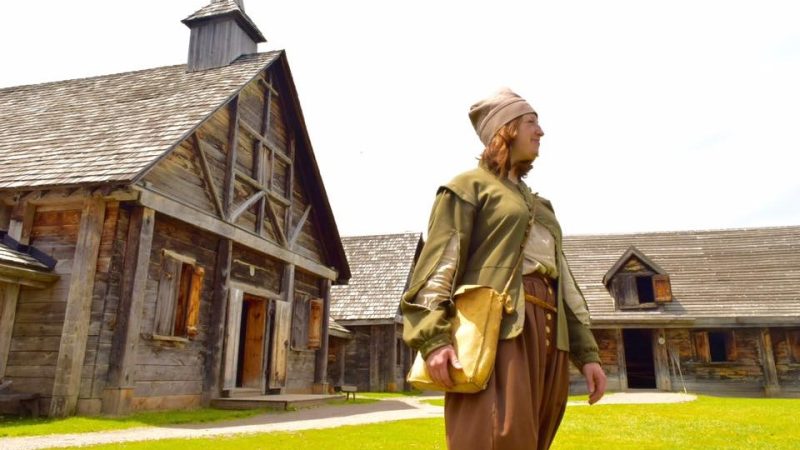 A costumed historical interpreter stands in North Court at Sainte-Marie among the Hurons