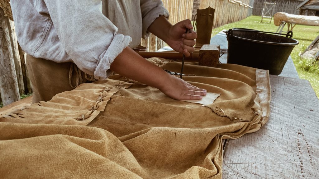 Une interprète historique autochtone à travailler sur un morceau de cuir - le début d&#039;une paire de moccasins