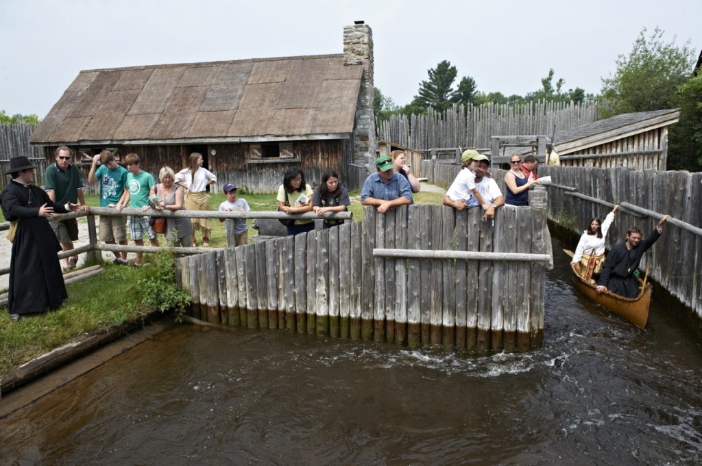 Plusieurs visiteurs et interprètes historiques costumés à regarder une demonstration du canal à Sainte-Marie