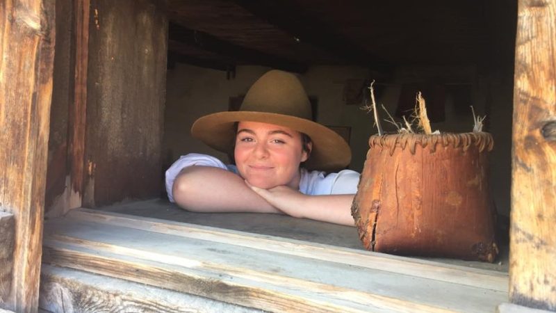 A smiling student interpreter stands in a window