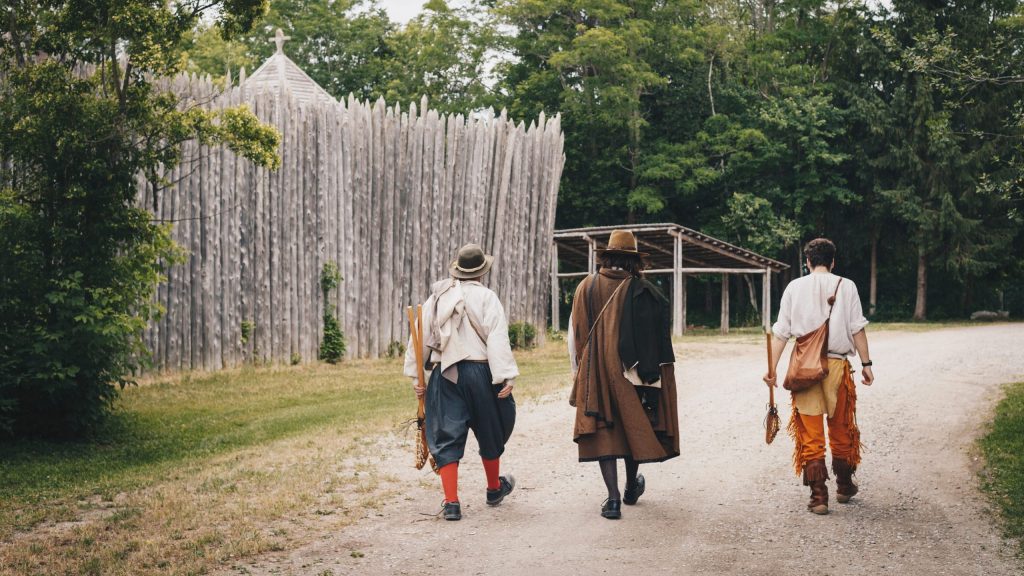 Trois interprètes historiques costumés à marcher ensemble le long de la route qui longe Sainte-Marie