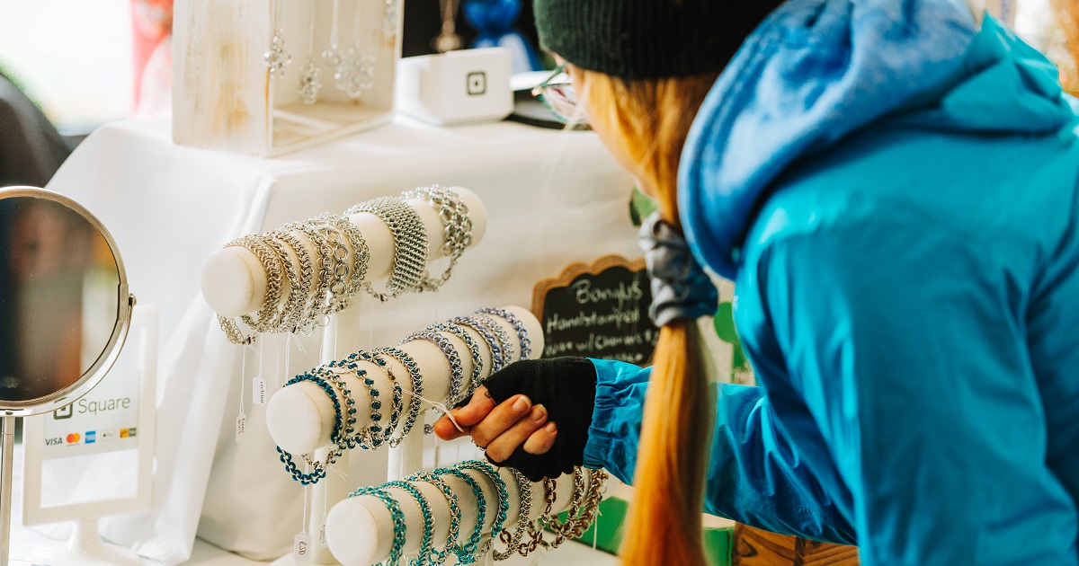 A guest looking at a price tag on a bracelet at a vendor sale at Sainte-Marie
