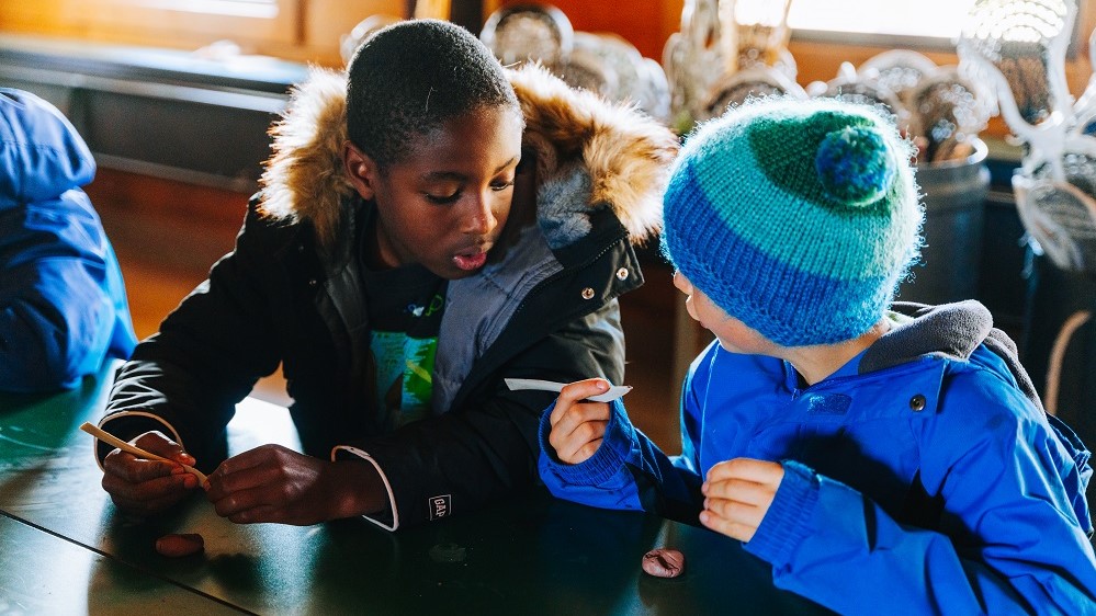 Two boys making clay okies inside the education centre at Sainte-Marie among the Hurons