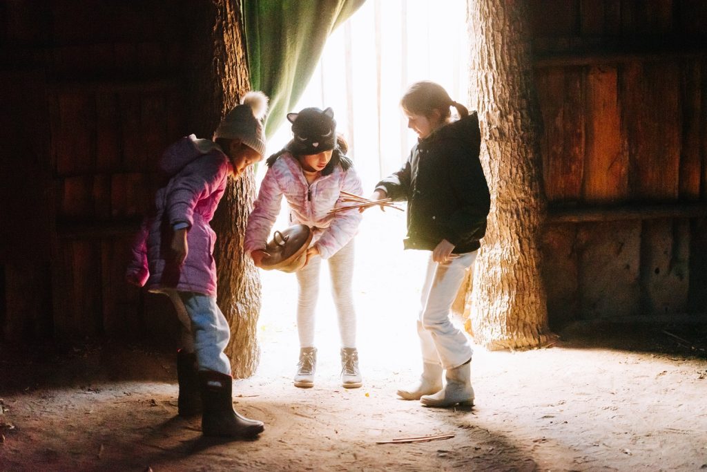 Three young guests of Sainte-Marie among the Hurons play games inside the longhouse