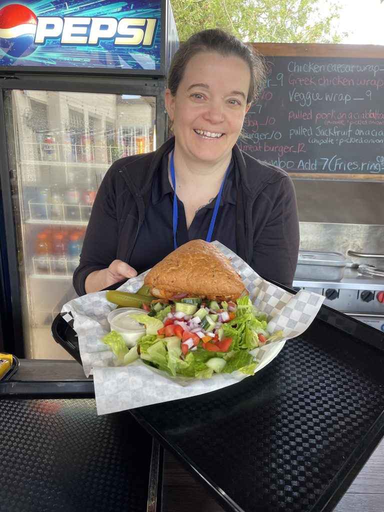 Restauranteur, Tammy, holds a plate with pulled jackfruit and salad