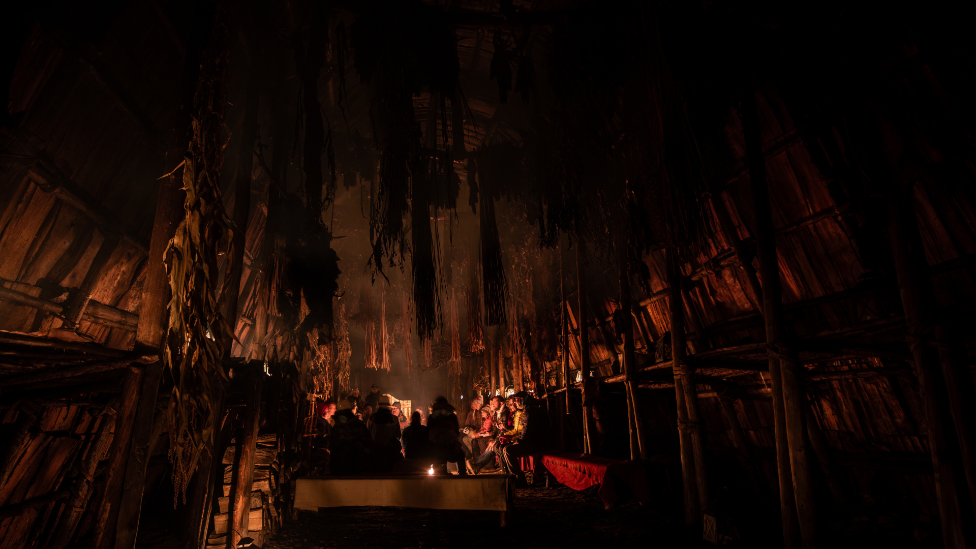 People gathering in the longhouse around a fire, at night
