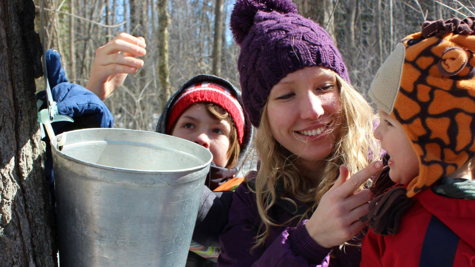 A mom gives her two young kids a sample of sweetwater to taste