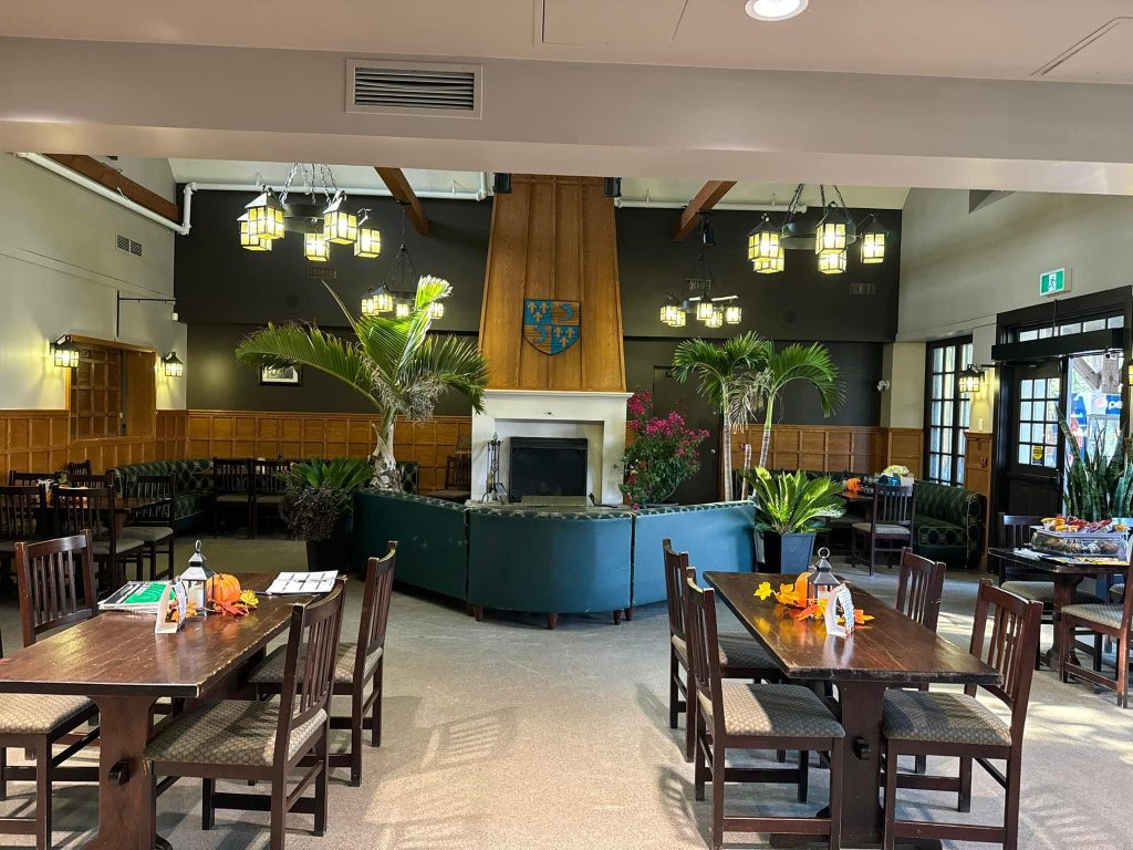 Interior of restaurant with tables, chairs, and large couch in front of fireplace
