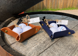 brown and blue leather bowls in three golf balls each and golf tees including the metal one