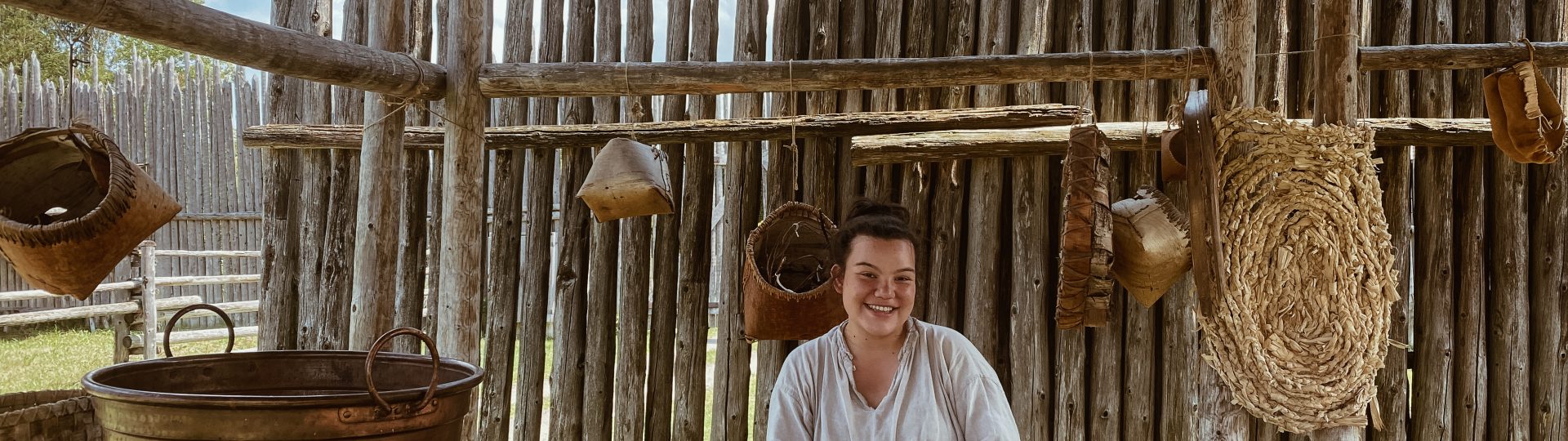 Two historical interpreters in a canoe travel the palisaded waterway at Sainte-Marie among the Hurons