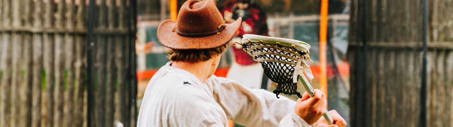 A historical interpreter throws a lacrosse ball into a speed net