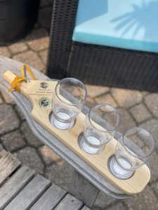 Wooden beer flight board with empty glasses on Muskoka chair arm
