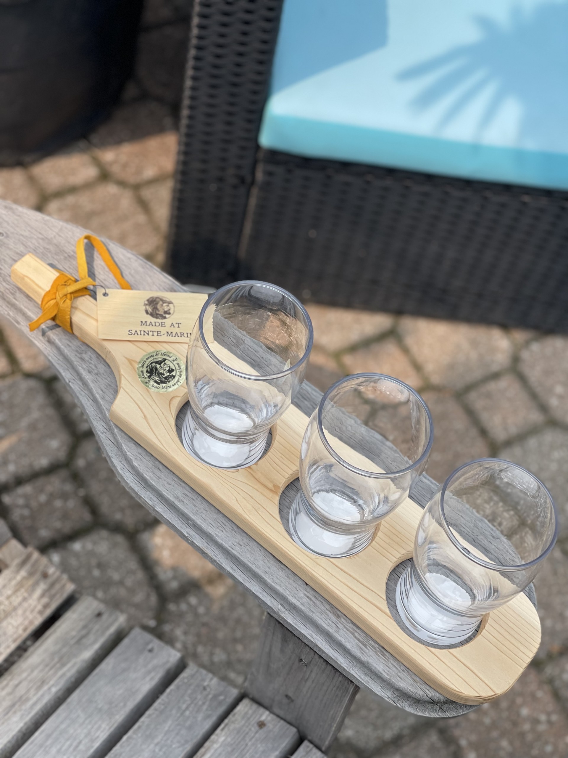 Wooden beer flight board with empty glasses on Muskoka chair arm