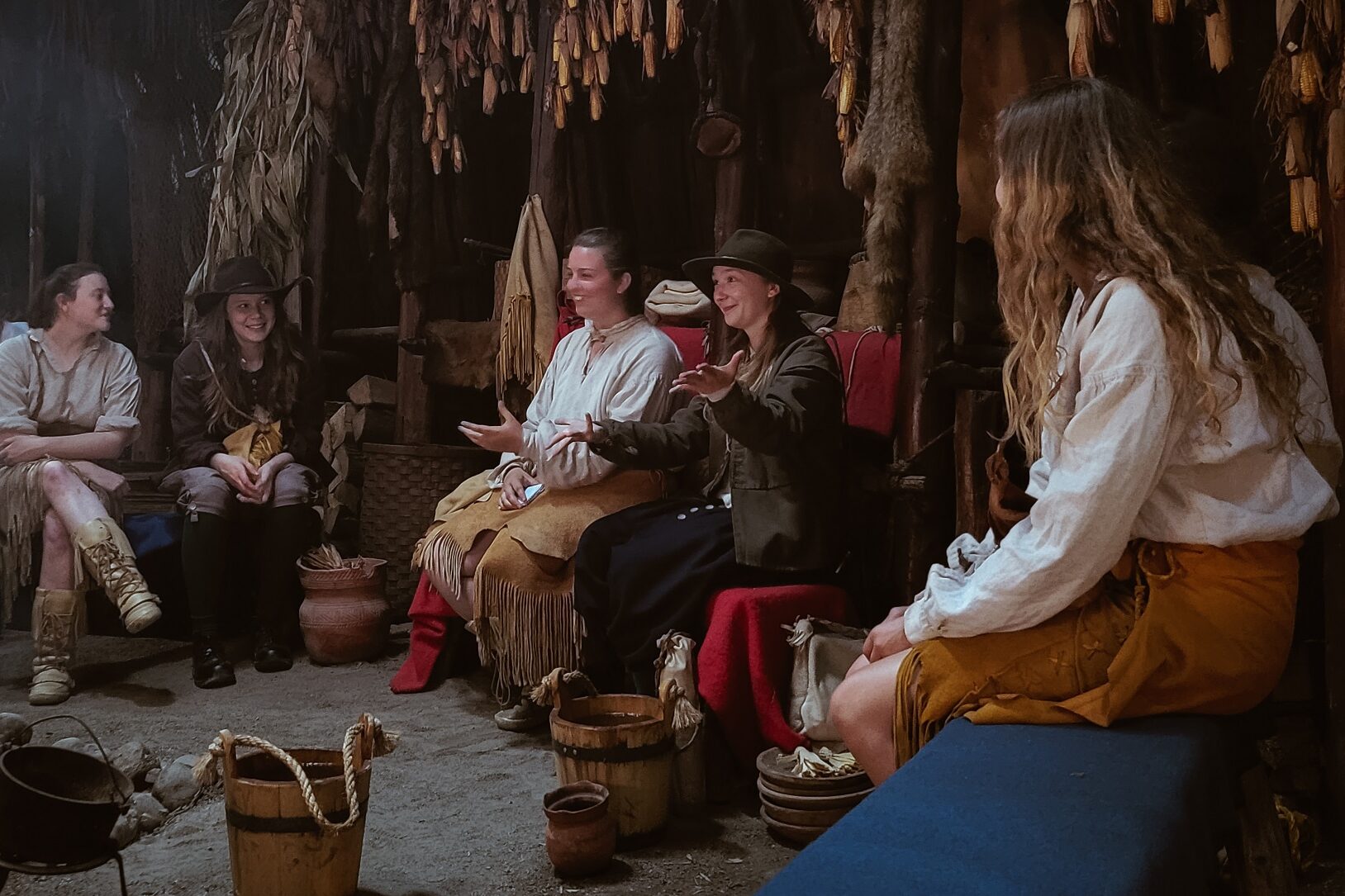 A group of costumed interpreters talking in the longhouse at Sainte-Marie.