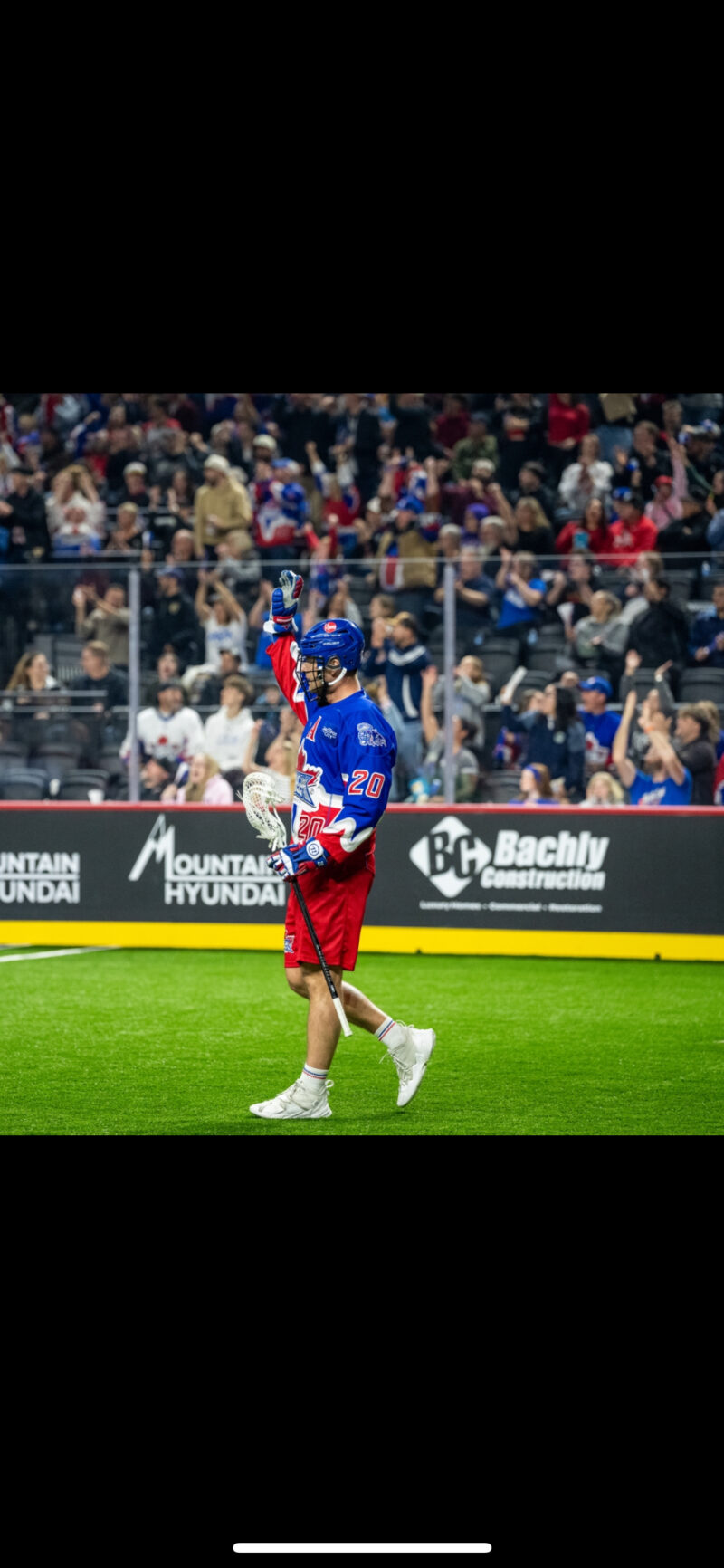 Chris Boushy of the Toronto Rock standing with lacrosse stick in front of glowing backdrop